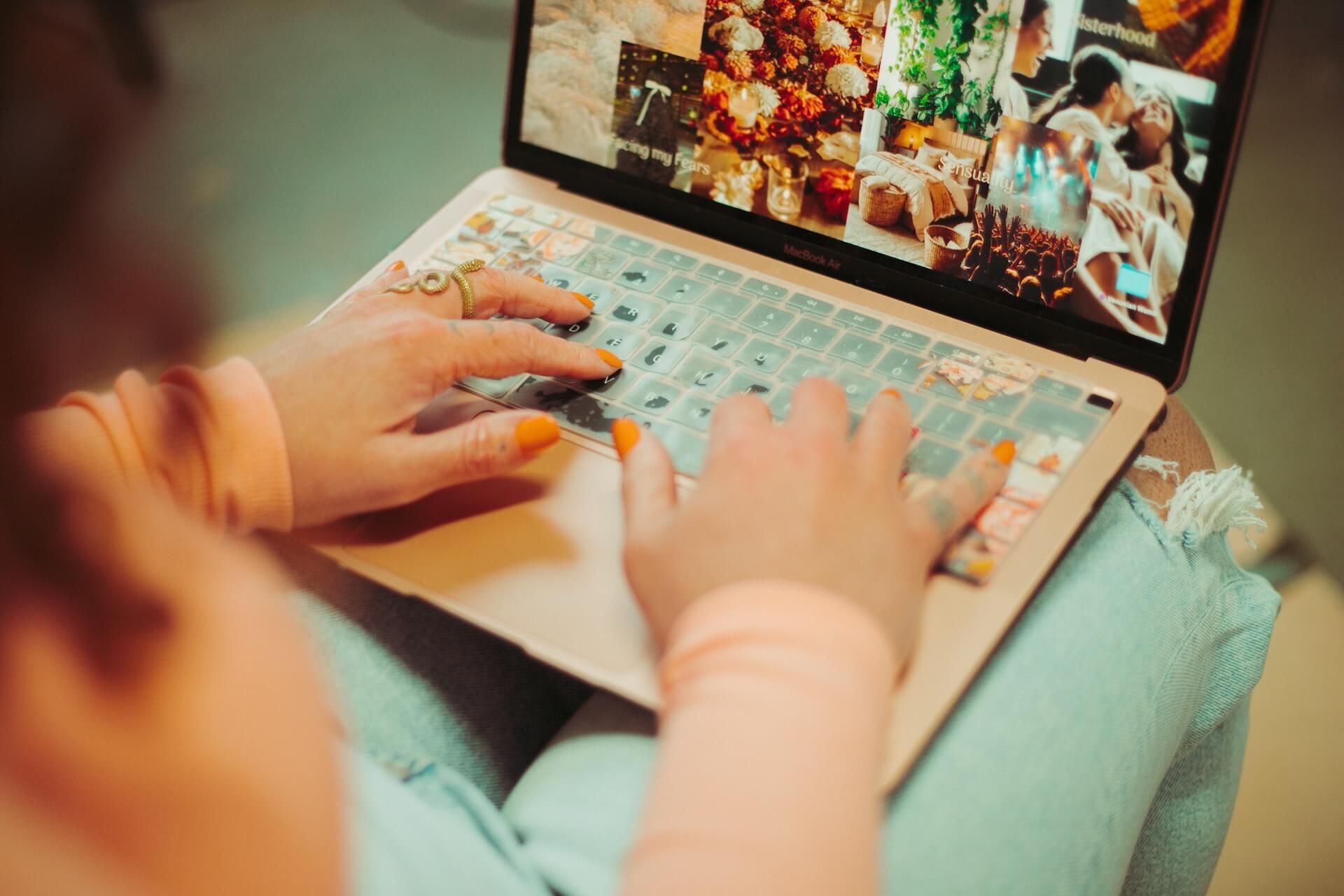 A woman is typing on a laptop computer with a collage of pictures on the screen.