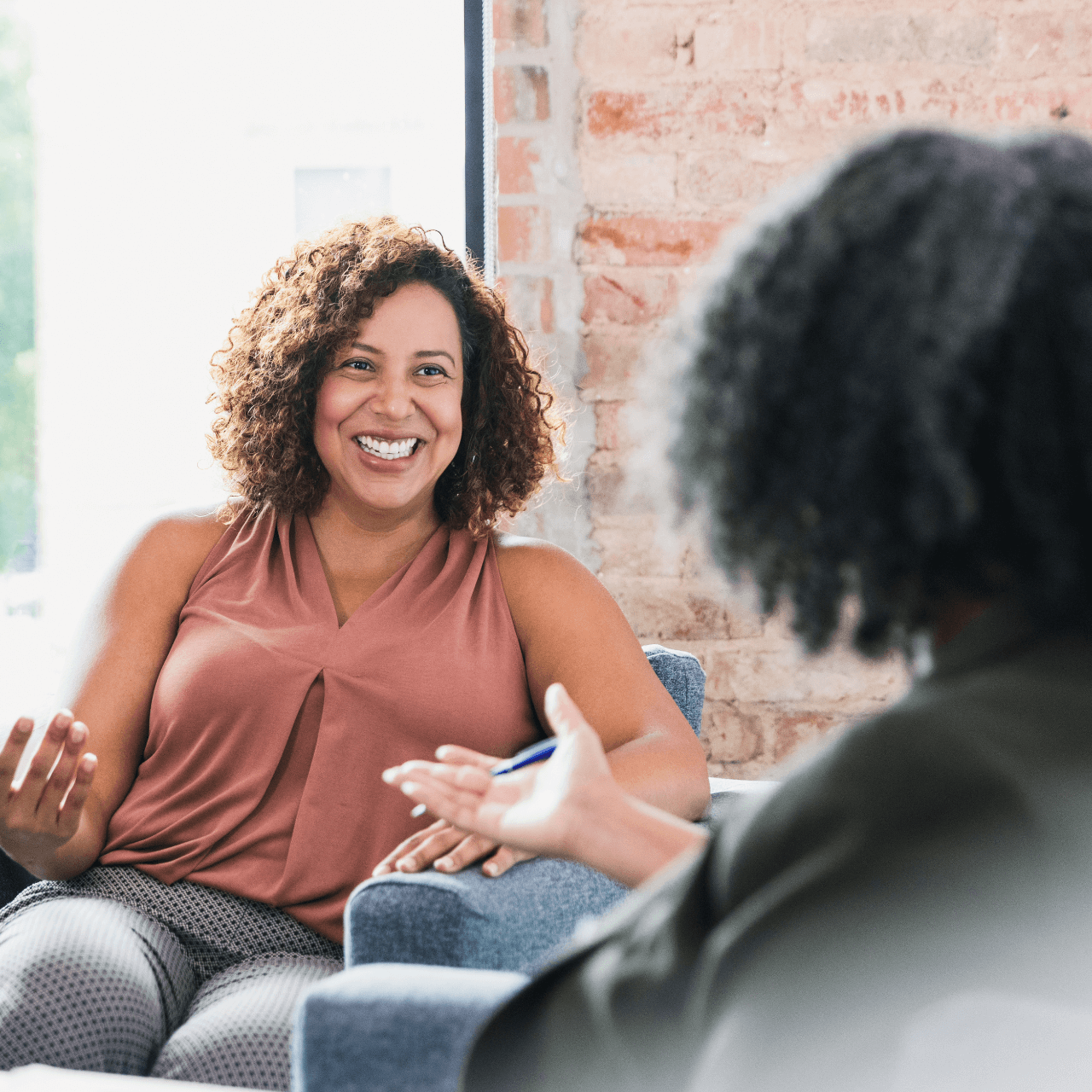 A woman is sitting in a chair talking to another woman.