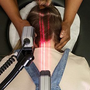 A person receiving laser therapy on their neck; red beams of light are visible.