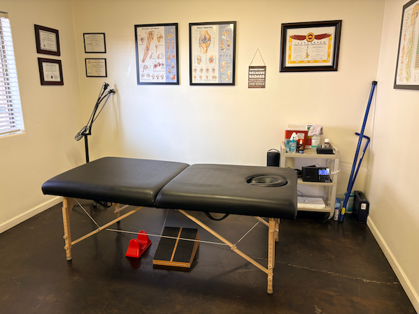 Massage therapy room with massage table, medical charts, and supplies.