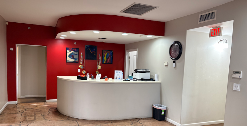 B2Y Reception area with red accent wall, curved white desk, and artwork.
