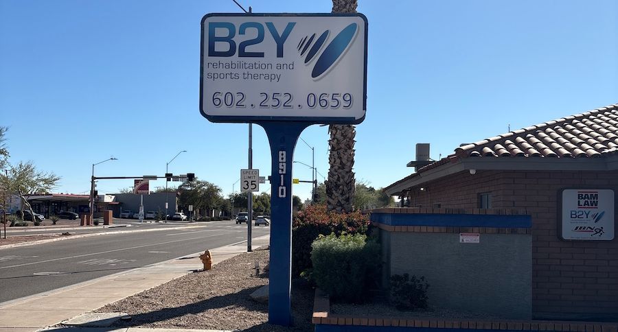 Sign for B2Y Rehabilitation and Sports Therapy with a phone number on a street.