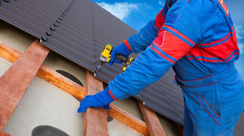 Man Worker Uses a Power Drill on The Roof — Roof Painting in Wingham, NSW