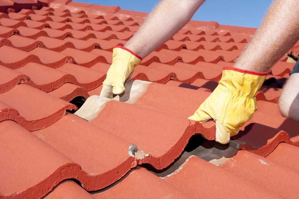 Worker With Yellow Gloves Replacing Red Tiles — Roof Painting in Forster