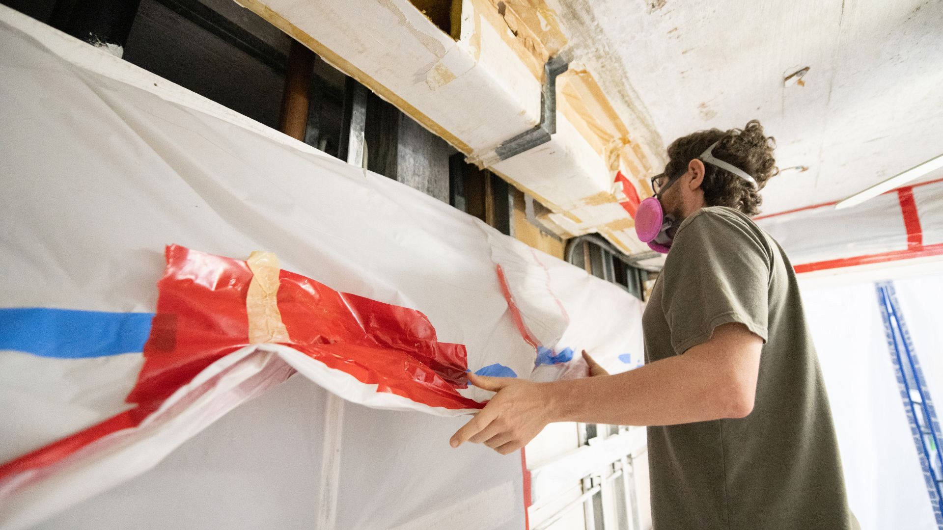a man wearing a mask is working on a wall .