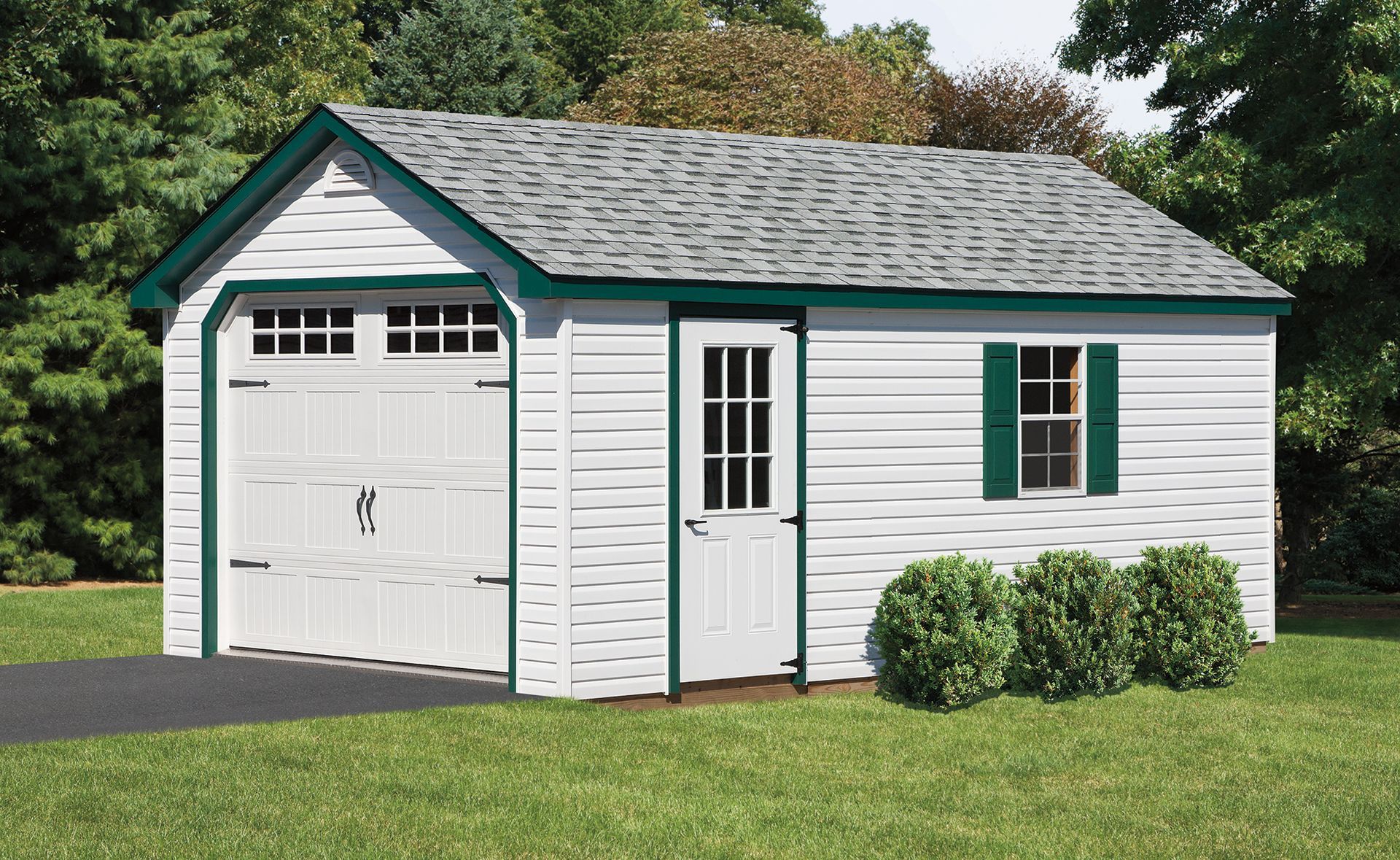 White shed with a gray roof and green trim, set on green grass.