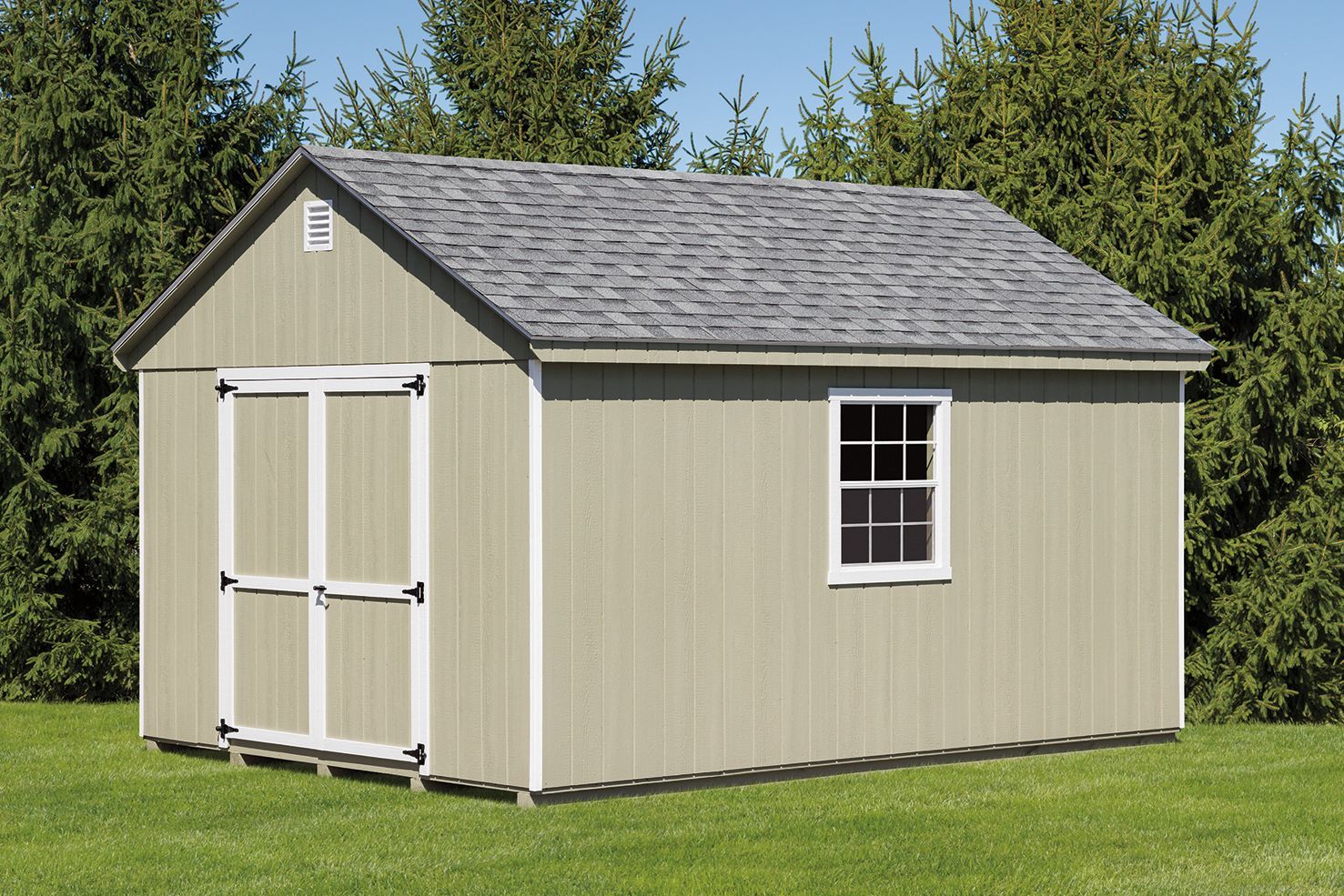 Tan shed with gray roof and a single window, sitting in a grassy yard, with trees in the background.