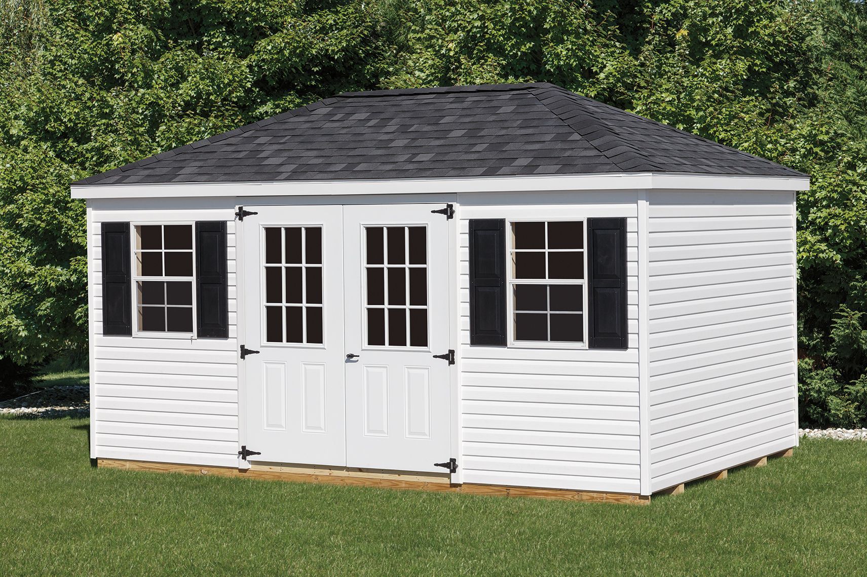 White storage shed with black shutters, doors, and roof on a grassy lawn.
