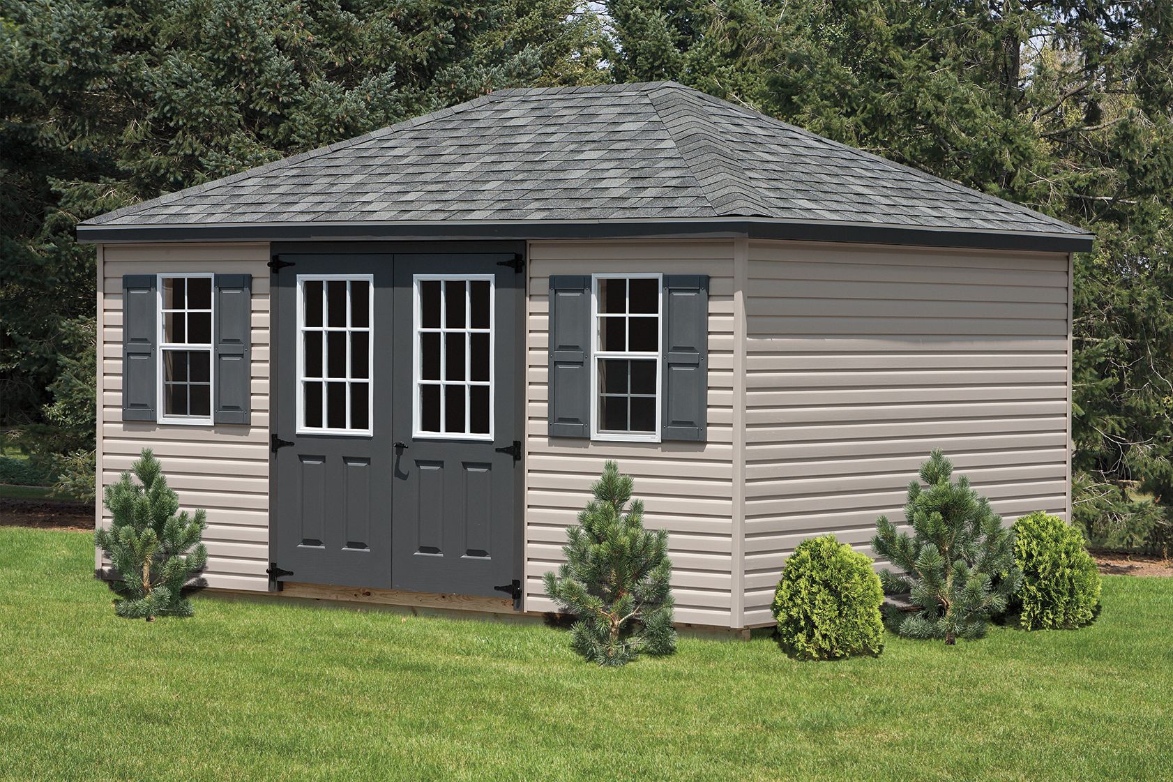 Tan shed with gray roof, doors, and shutters; windows on either side of the doors; on a grassy lawn.