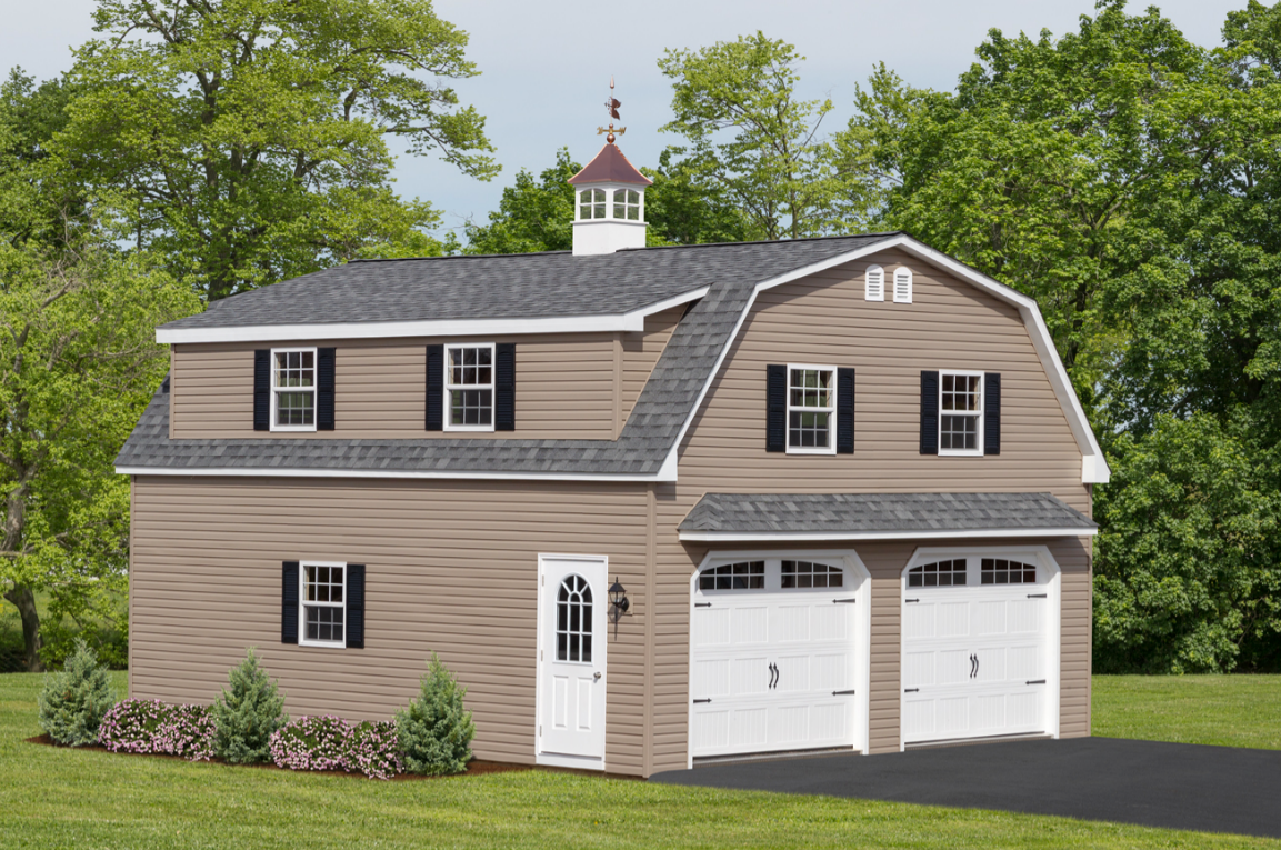 Two-story tan and white barn with two garage doors and a cupola; set in a grassy yard.