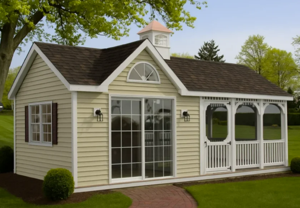Small, light yellow cottage with brown roof and white porch, set on green grass.