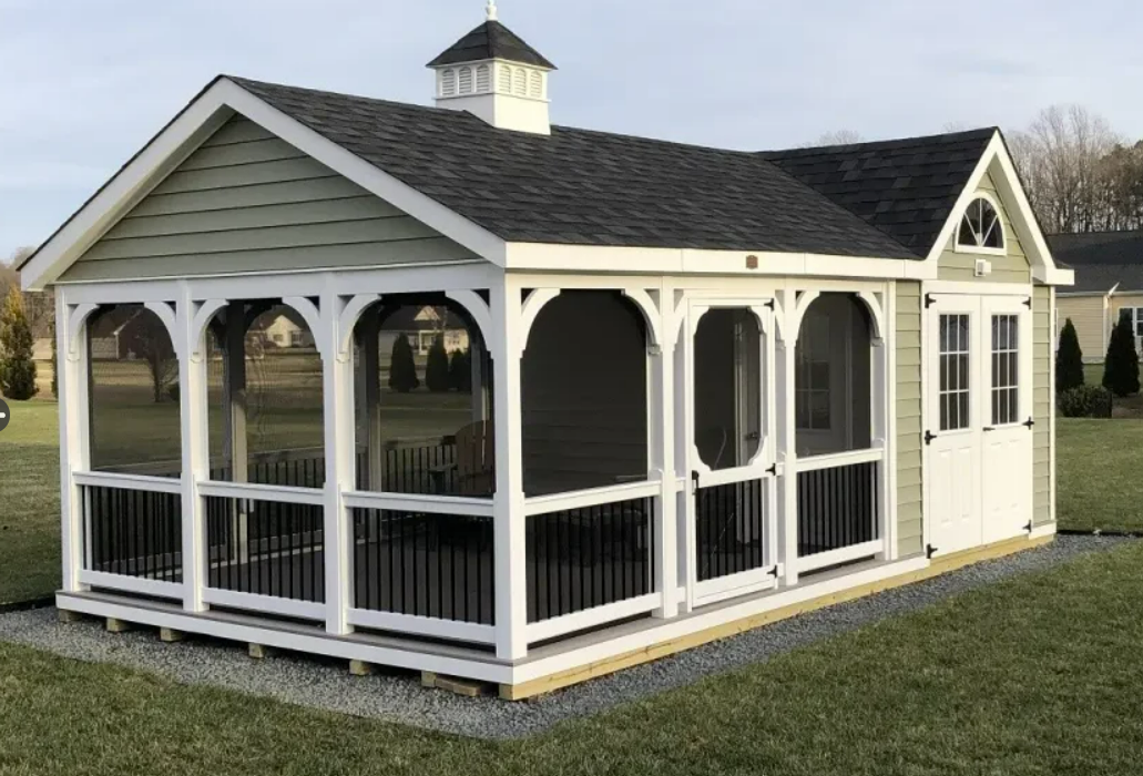 Green and white screened porch with black railing and dark roof, in a grassy setting.