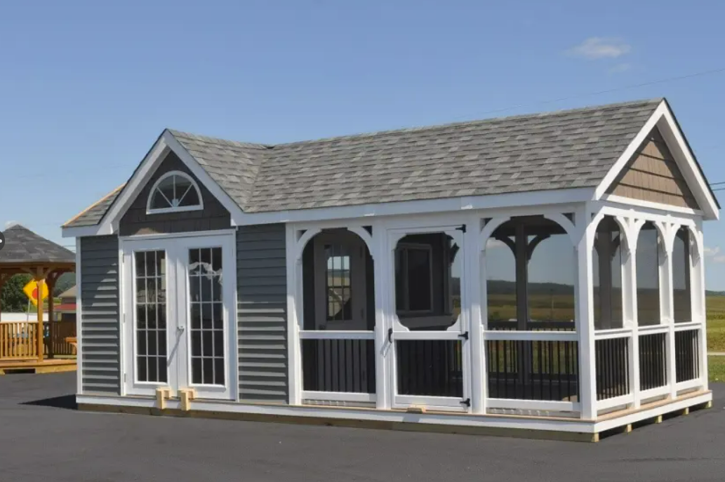 Small gray shed with a screened-in porch and white trim under a clear blue sky.