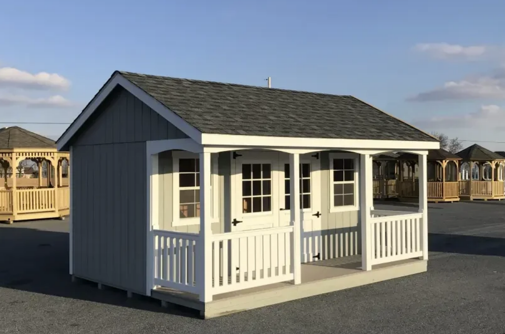 Gray shed with white trim, porch, and a gray shingle roof.