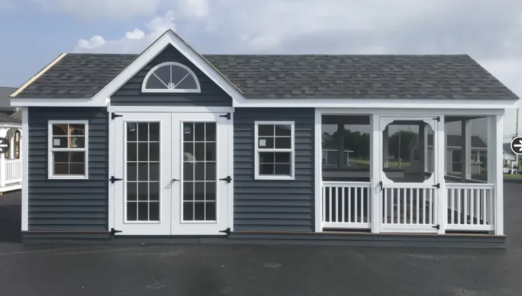 Dark blue shed with white trim, double doors, two windows, and a screened porch under a gray shingled roof.