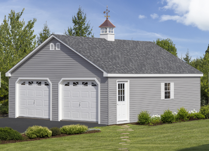 Gray two-car garage with white doors and a cupola; set on a lawn with bushes and trees.