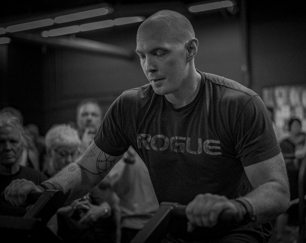 A man is riding an exercise bike in a gym in a black and white photo.