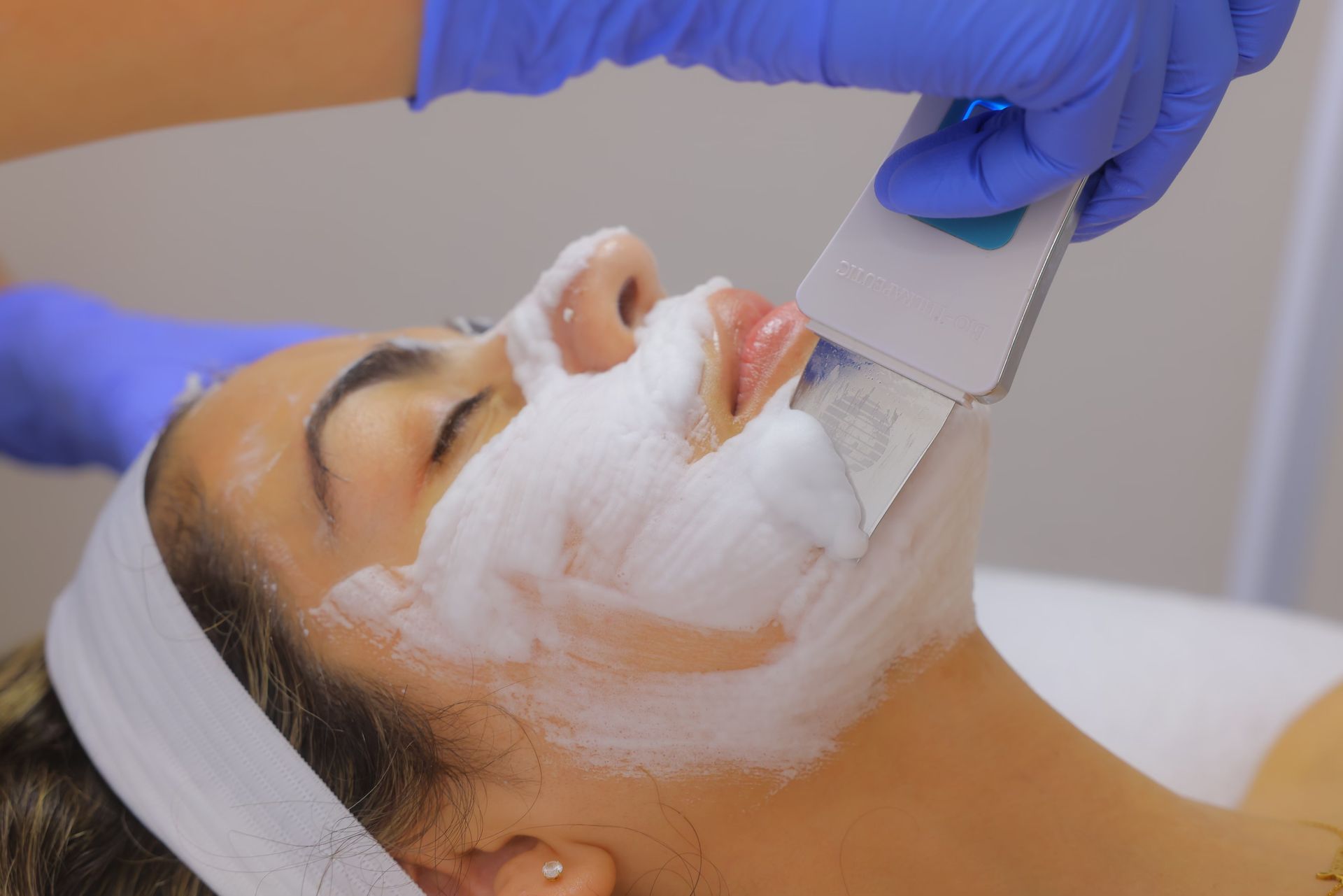 A woman is getting a facial treatment with foam on her face.