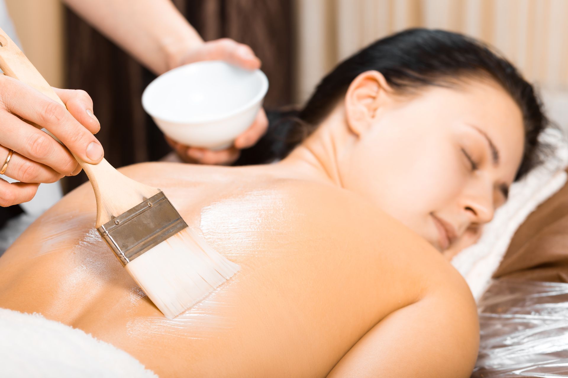 A woman is getting a massage with a brush on her back.