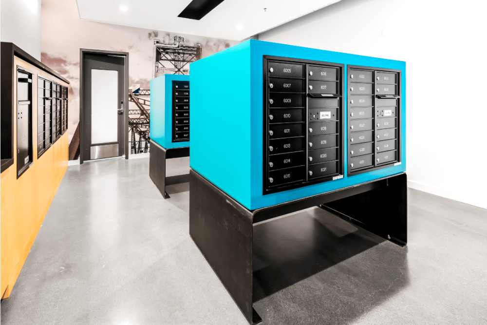 Interior mailroom with blue mailbox units along a hallway.