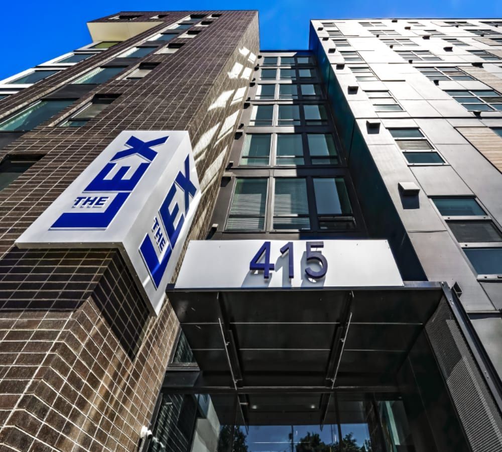 Exterior view of a modern apartment building with a large 'THE LEX' sign and 415 at the entrance.