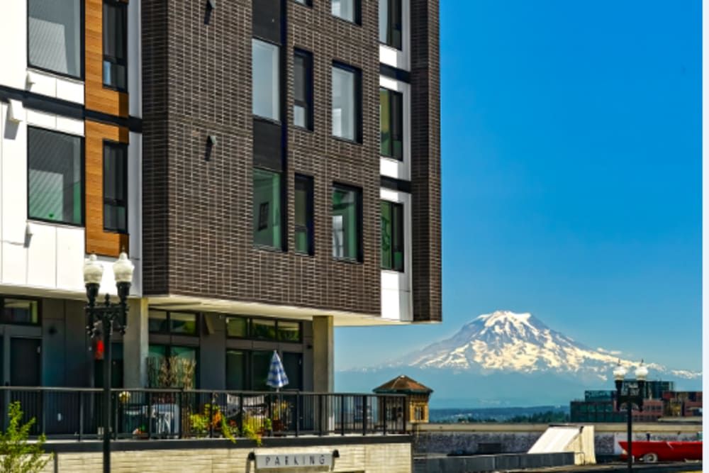 Exterior view of a modern apartment building with a mountain in the background.