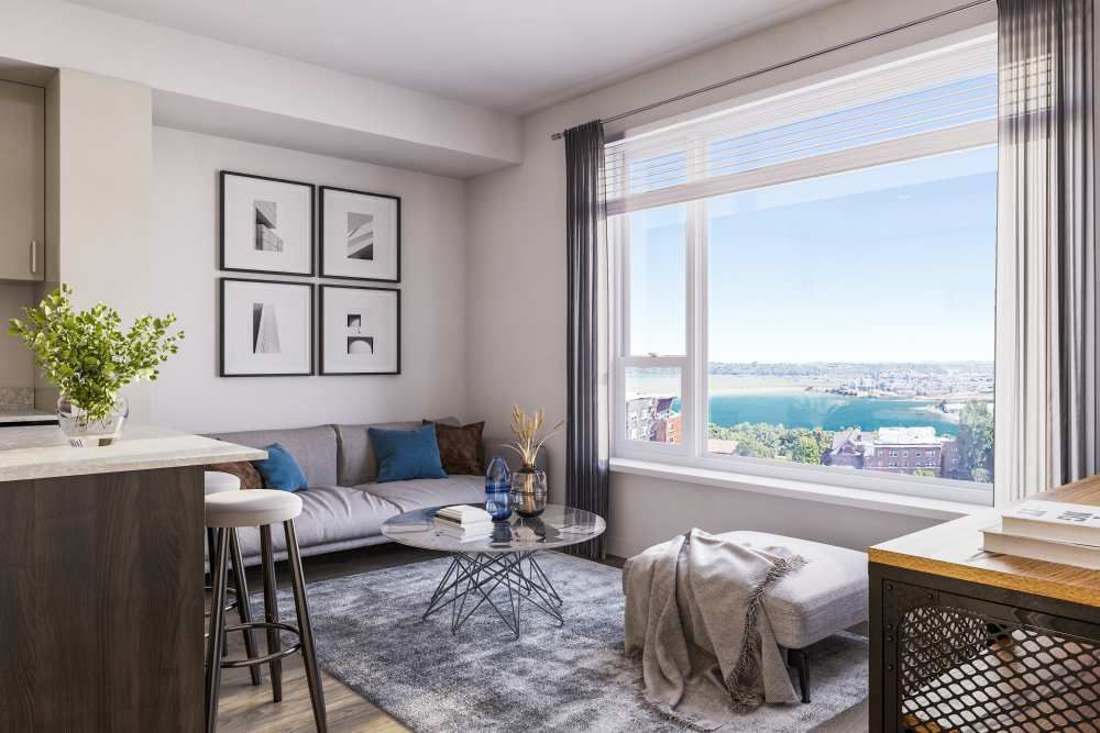 Interior living room in a modern apartment with a sofa, glass coffee table, and a large window view.