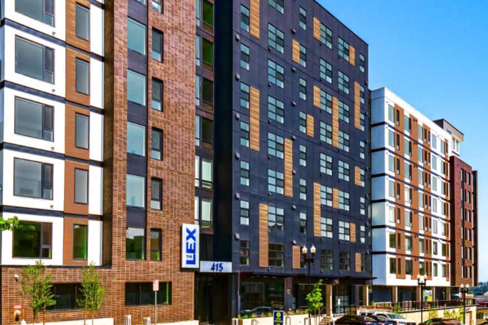 Exterior view of a modern apartment complex with multi-colored brick façades and signage at the entrance.