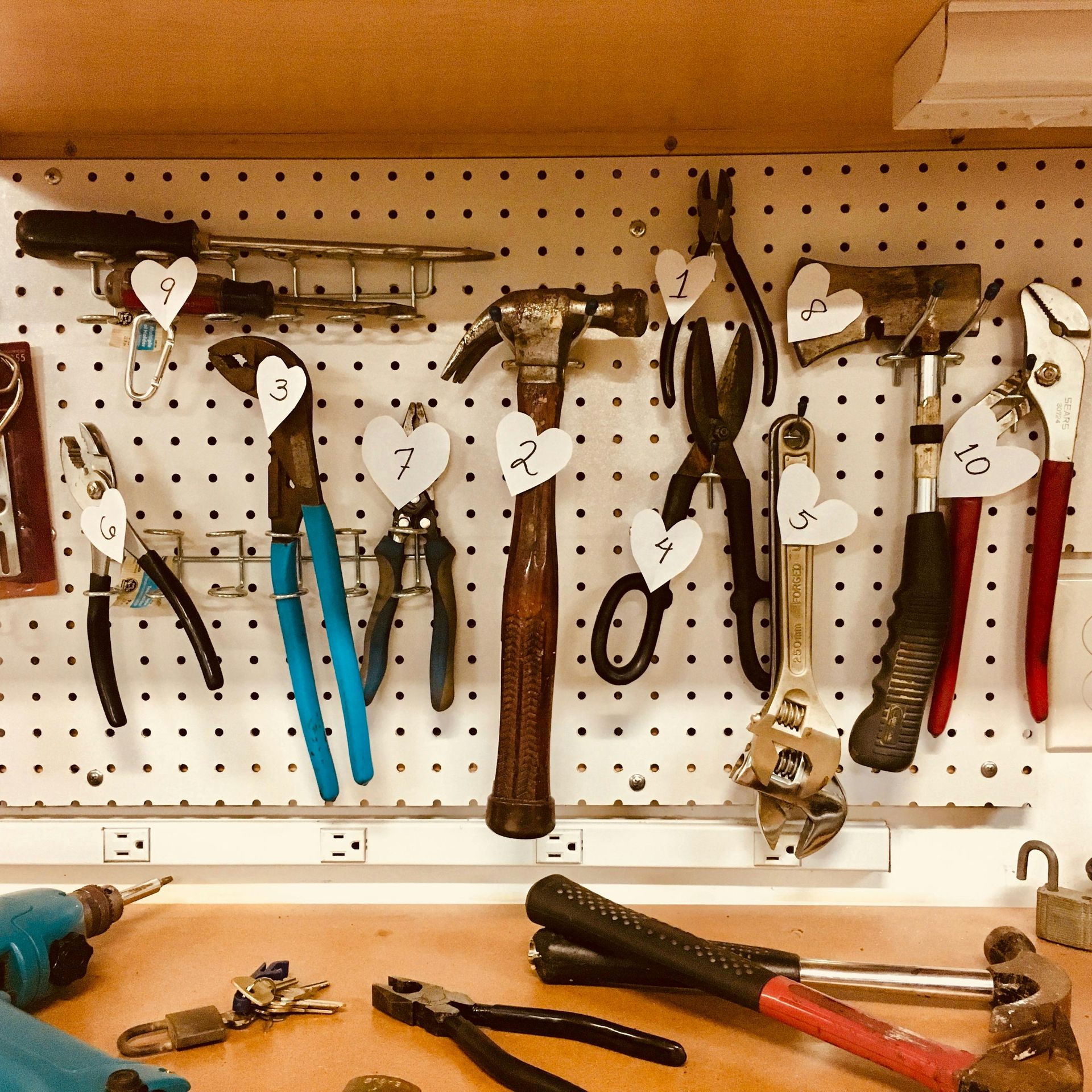A bunch of tools hanging on a wall including a hammer and pliers