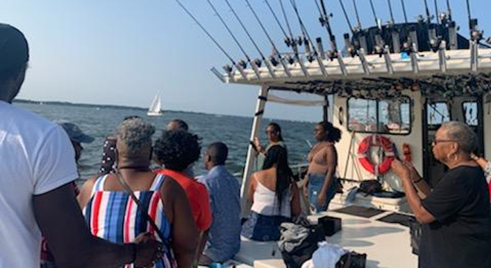 A group of people are standing on a boat in the water.