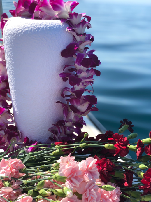 A white urn surrounded by pink and purple flowers