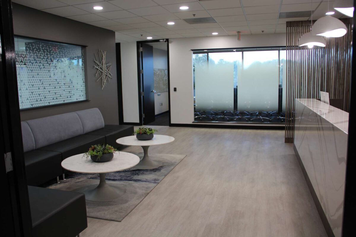 A hallway in a building with a lot of glass doors and a rug on the floor.