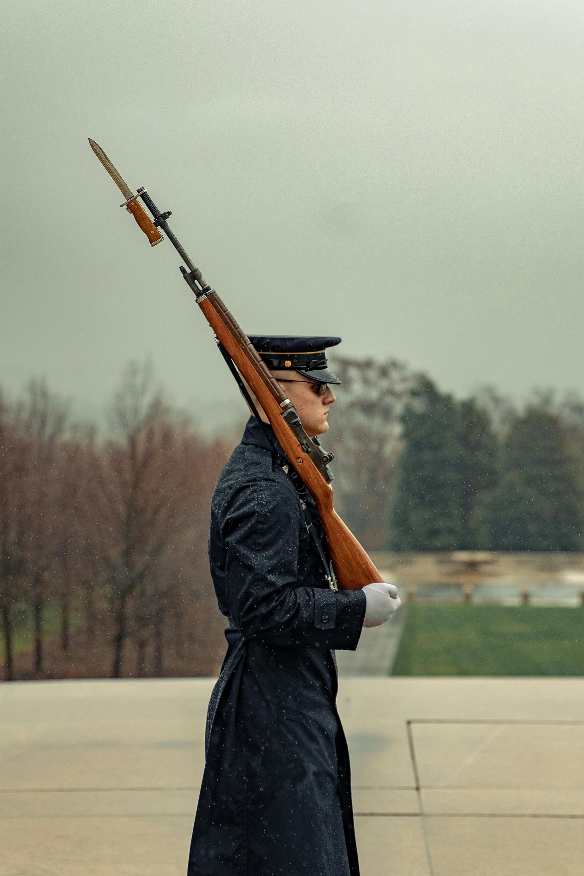 A man in a military uniform is holding an American flag in his hands.