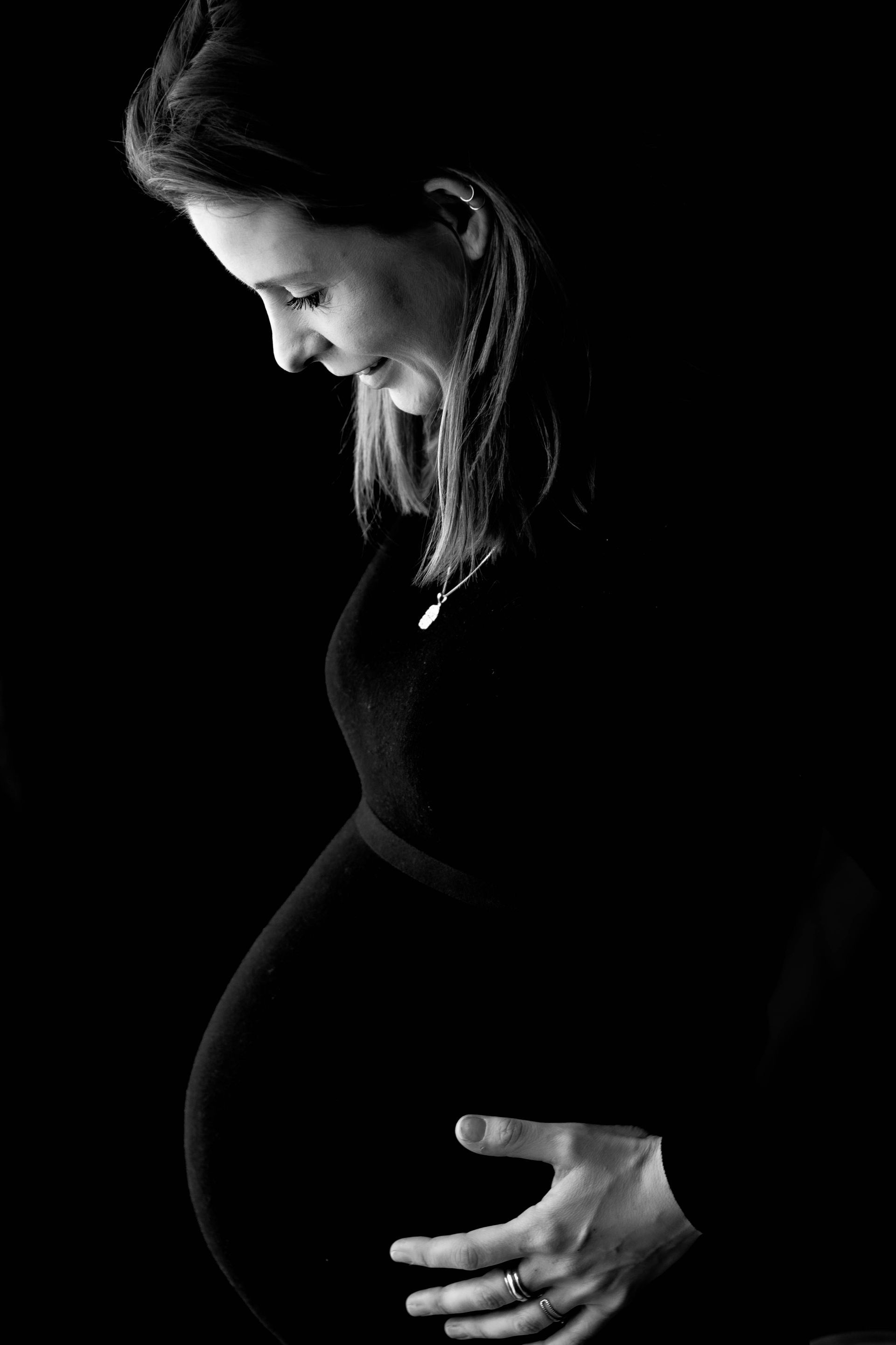Een zwangere vrouw houdt haar buik vast op een zwart-witfoto.