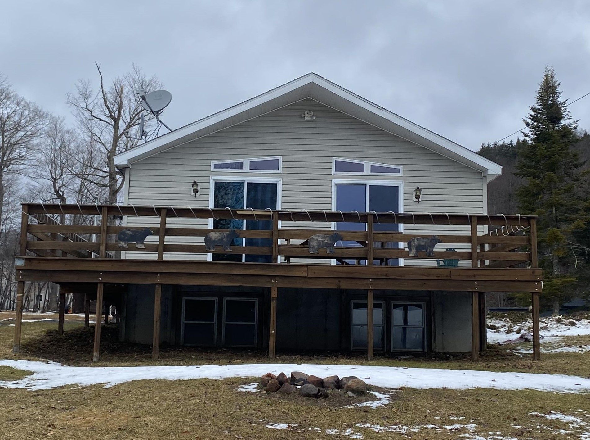 A house with a large deck and a fire pit in front of it.