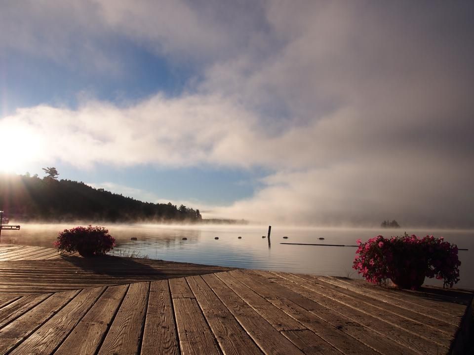 A foggy lake with a wooden dock in the foreground