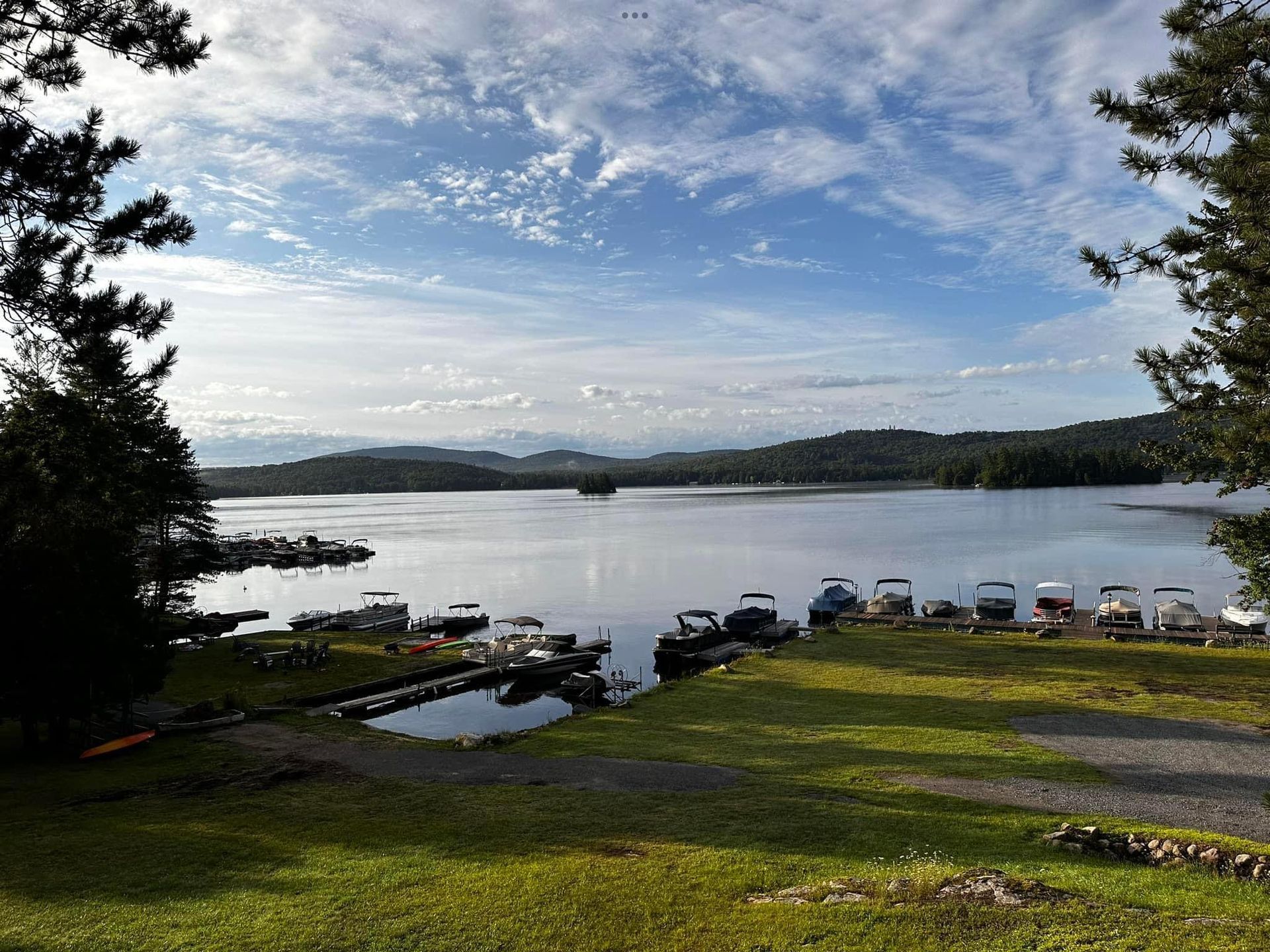 A row of boats are docked on the shore of a lake.