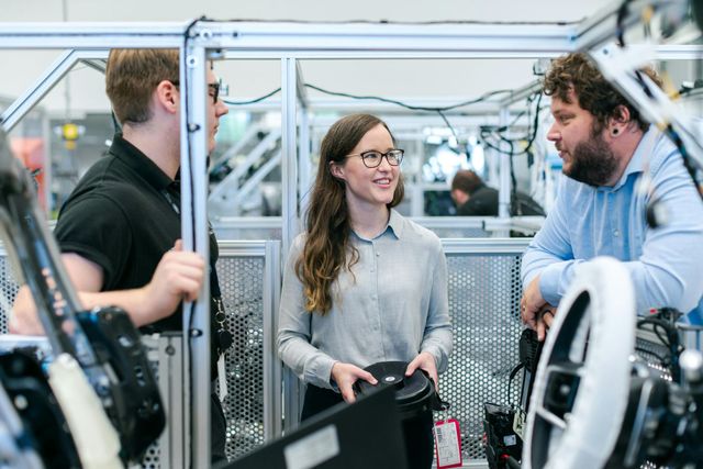 A group of people are standing around a machine in a factory.