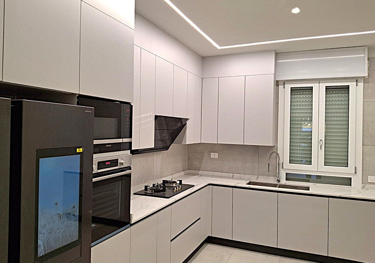 Moderna cucina bianca con mobili eleganti, ripiani ed elettrodomestici neri.