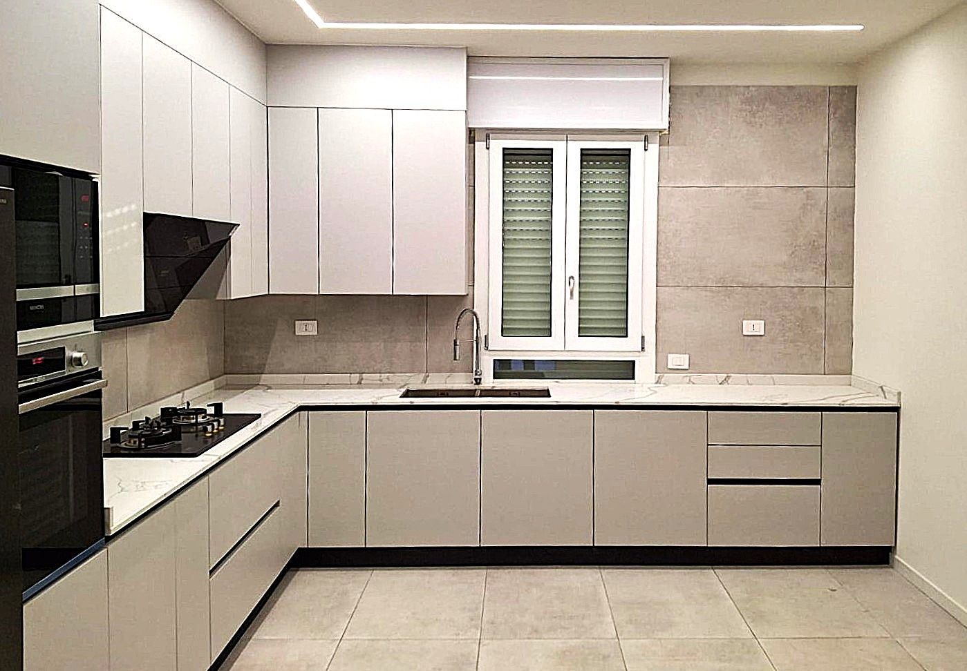 Cucina moderna con mobili, ripiani ed elettrodomestici grigio chiaro.