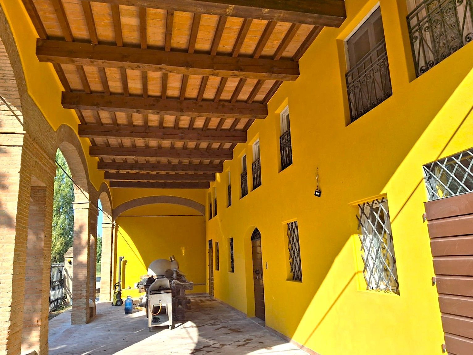 Edificio giallo con travi in ​​legno, portico ad arco e finestre con sbarre.