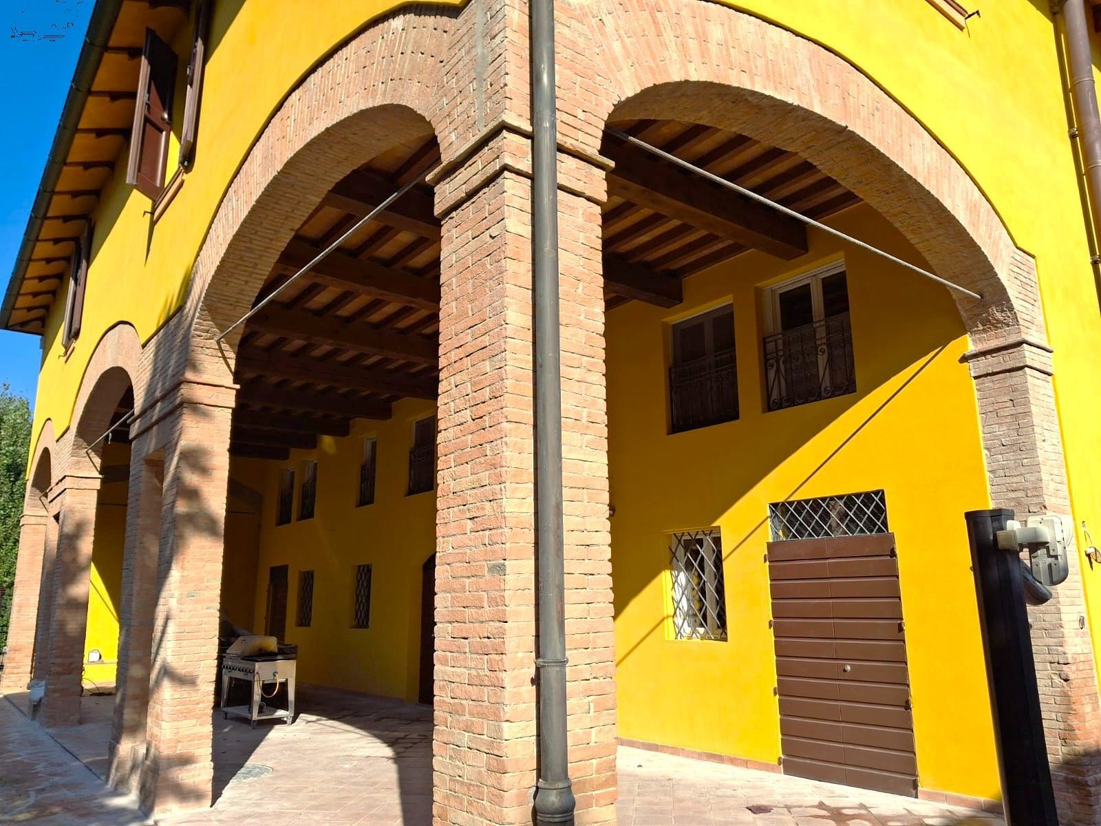 Edificio giallo con supporti in mattoni ad arco; ambiente esterno.