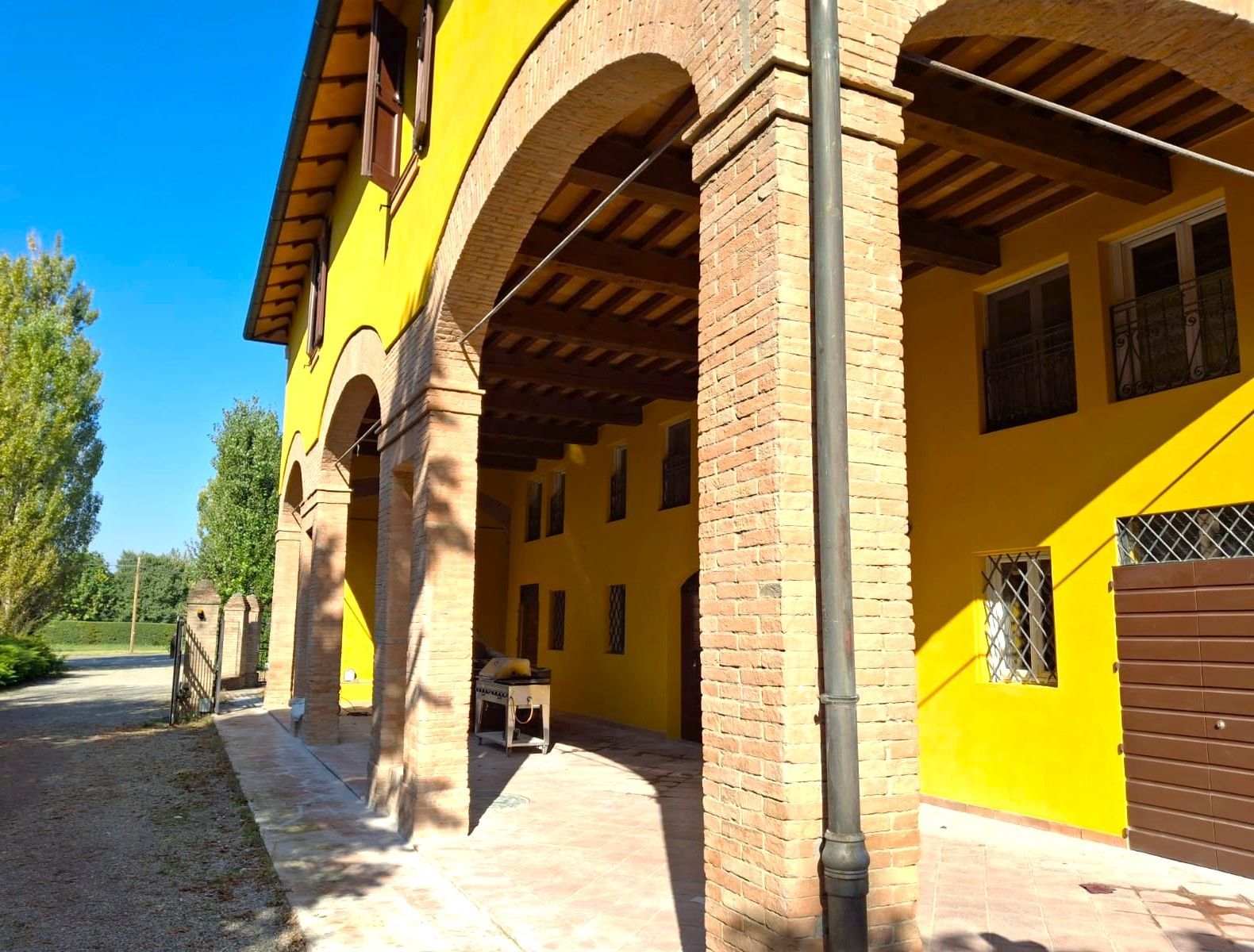 Edificio giallo con archi in mattoni, travi in ​​legno e piccole finestre, vista esterna.