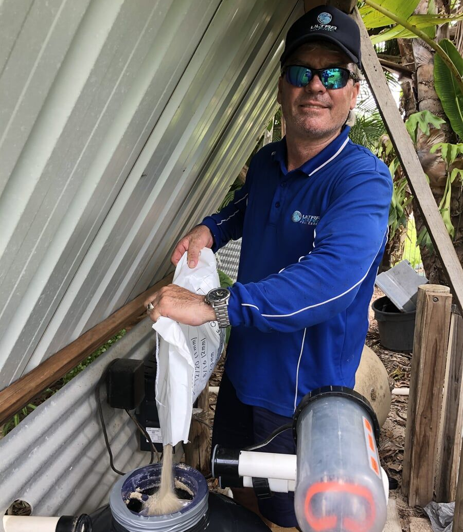 Pool Worker in Blue Overalls Refills Pool Water with A Pump — Ultra Clear Pool Care in Cranbrook, QLD