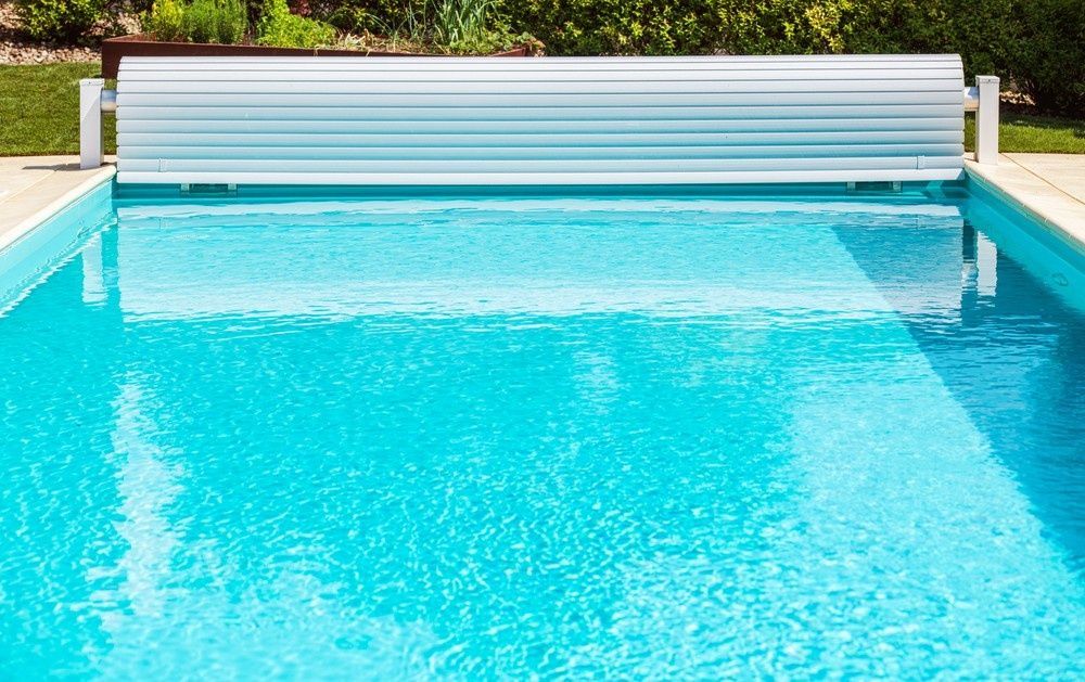 Swimming Pool with Partially Closed White Cover; Bright Blue Water — Ultra Clear Pool Care in Cranbrook, QLD