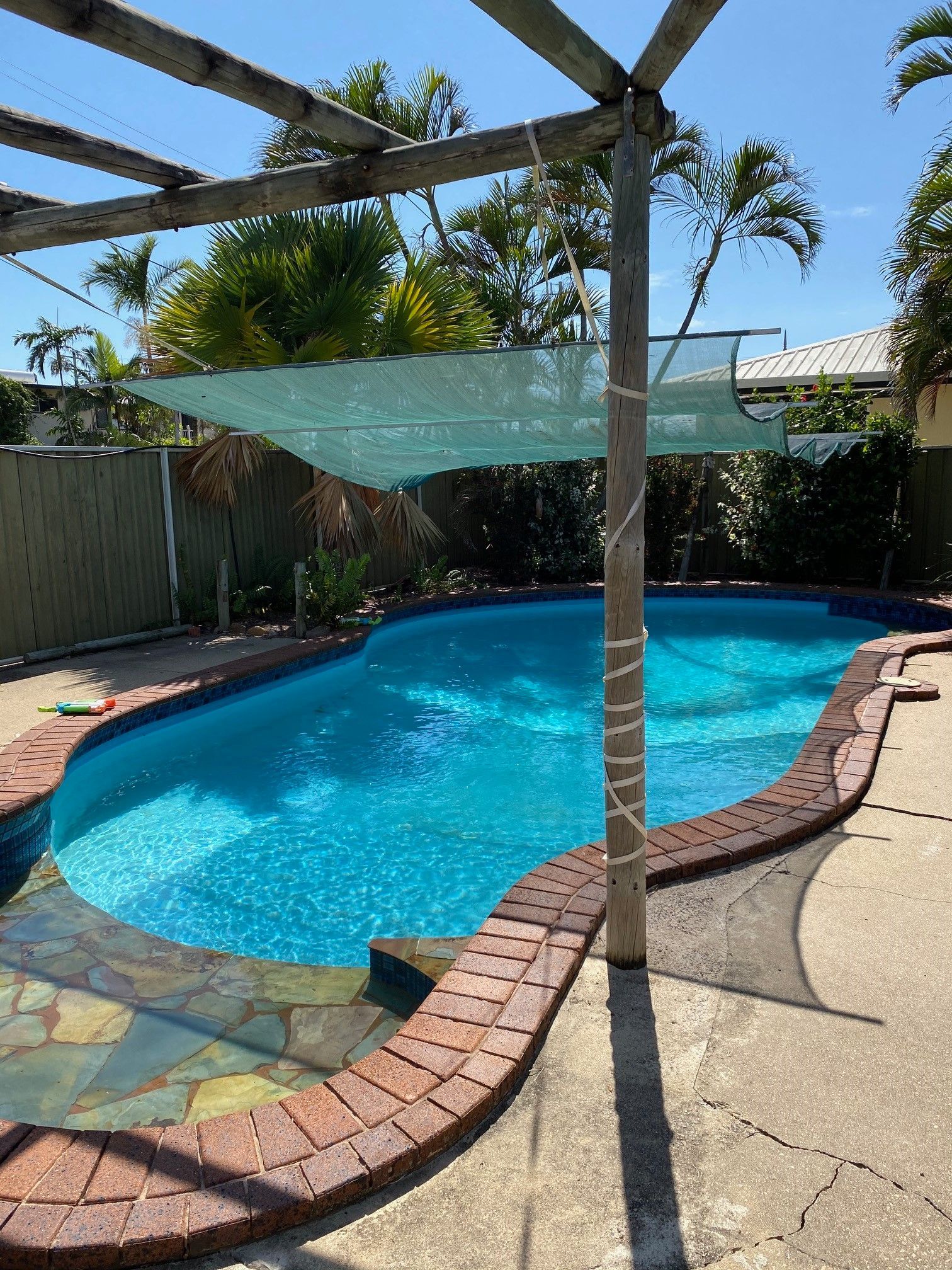 Pool with Blue Water, Brick Surround, and A Shade Cover on A Sunny Day — Ultra Clear Pool Care in Cranbrook, QLD