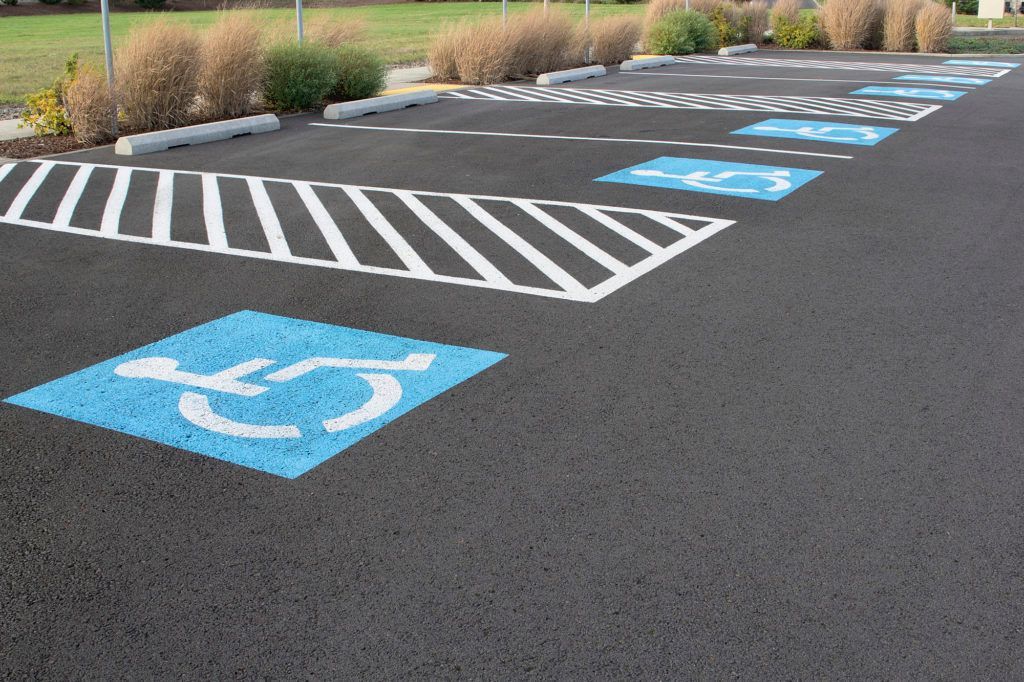 Parking lot with blue and white handicap symbols and striped access lanes.