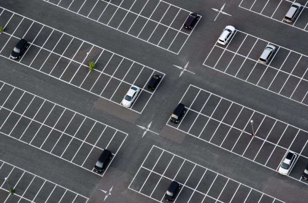 Overhead view of a mostly empty parking lot with several cars parked in spaces.