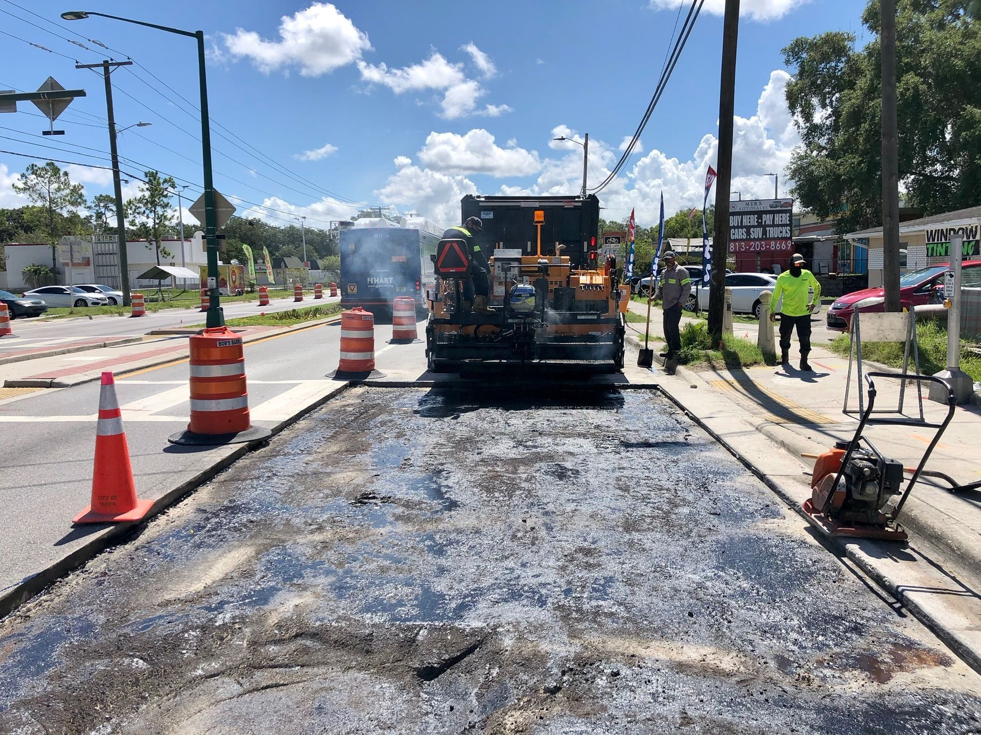 Yellow John Deere grader smoothing a dirt road surface.