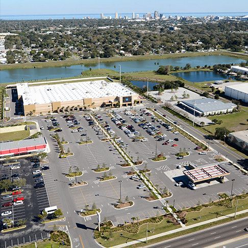 Aerial view of a large retail store with a large parking lot and a city skyline in the background.